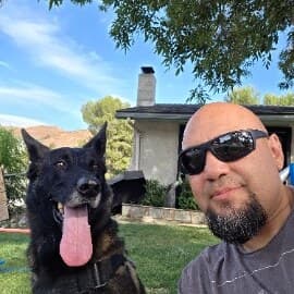 A founder of Pawnanigans outdoors with their Belgian Malinois